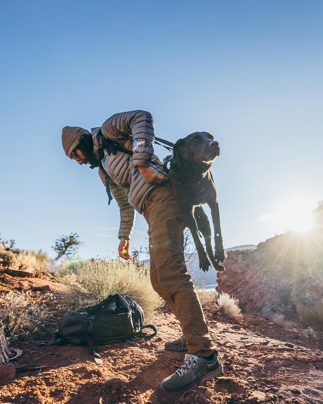 man lifting his injured black dog in the desert with the k-911 rescue sling