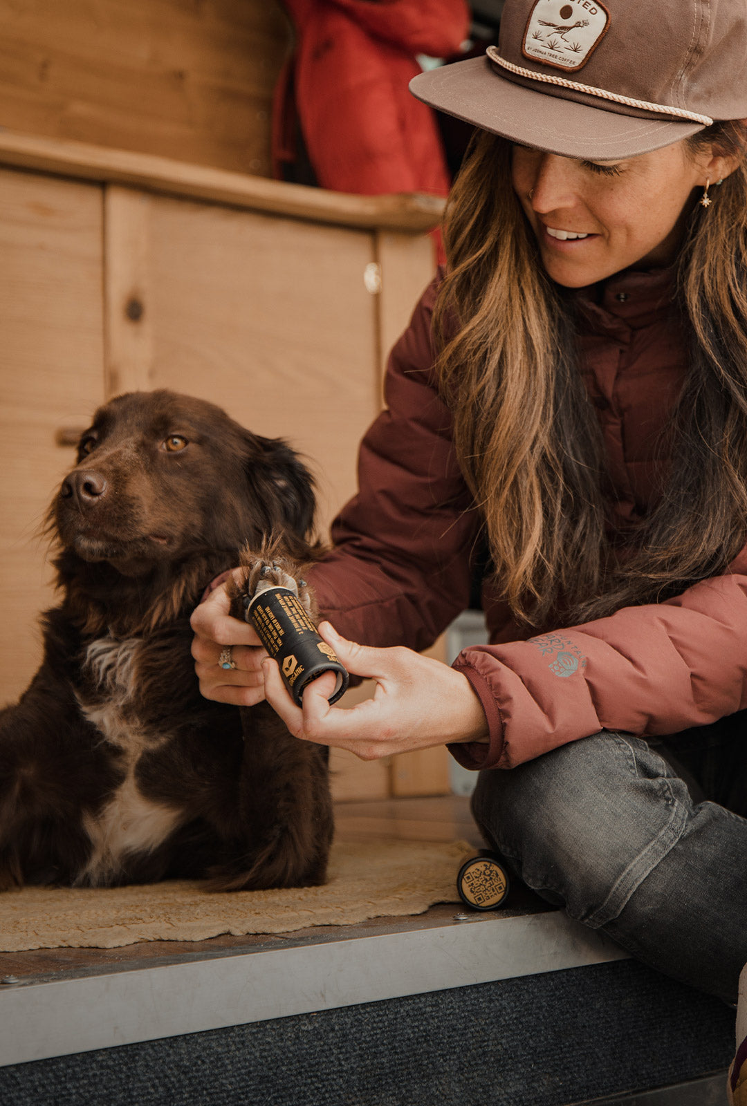 Woman applying saker paw balm to the paws of her dog