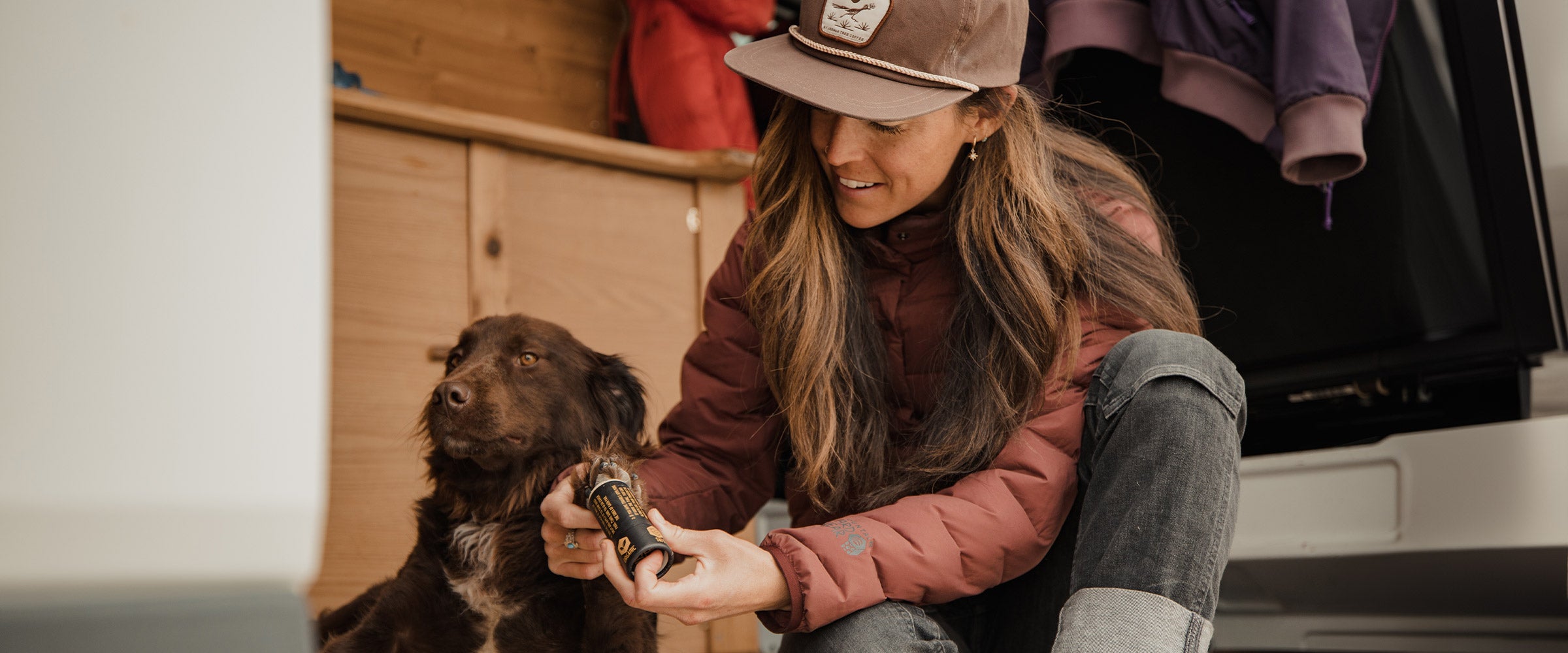 Woman applying saker paw balm to the paws of her dog