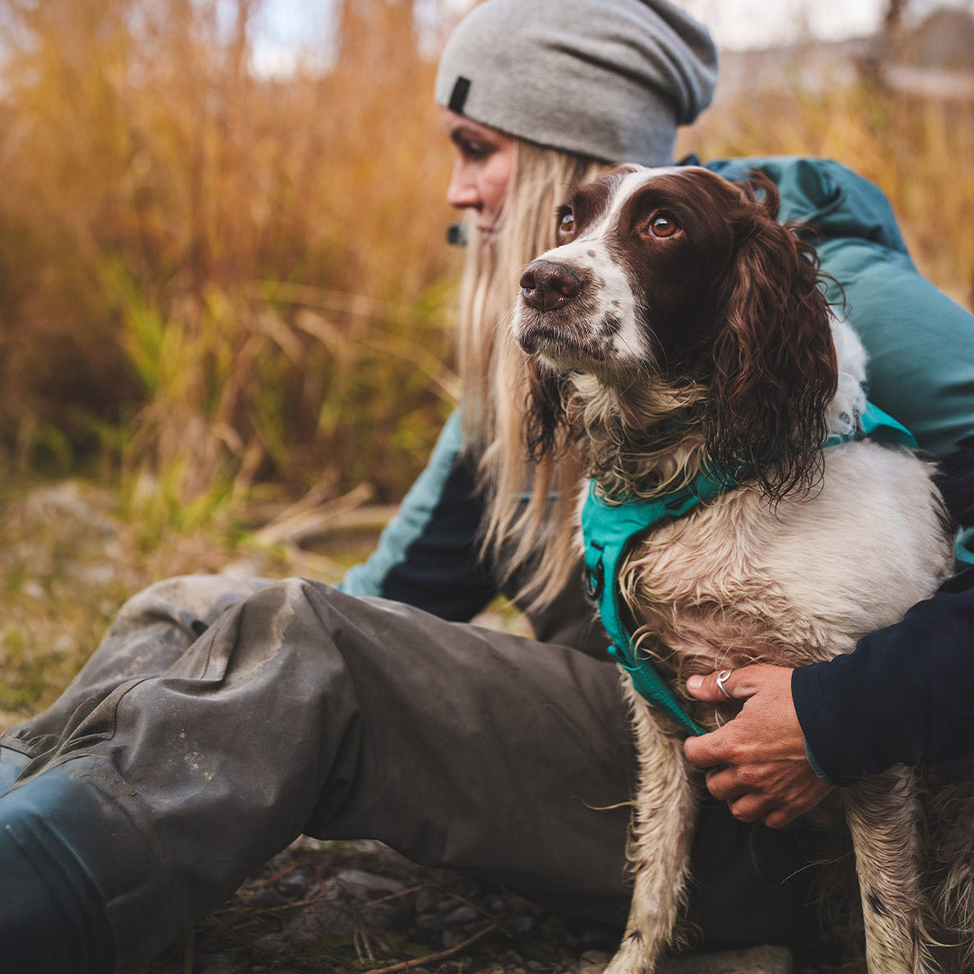 Paula shearer with her dog willow starting a bonfire next to the Bow River. Willow wears the Säker Muse harness in Skeena Teal