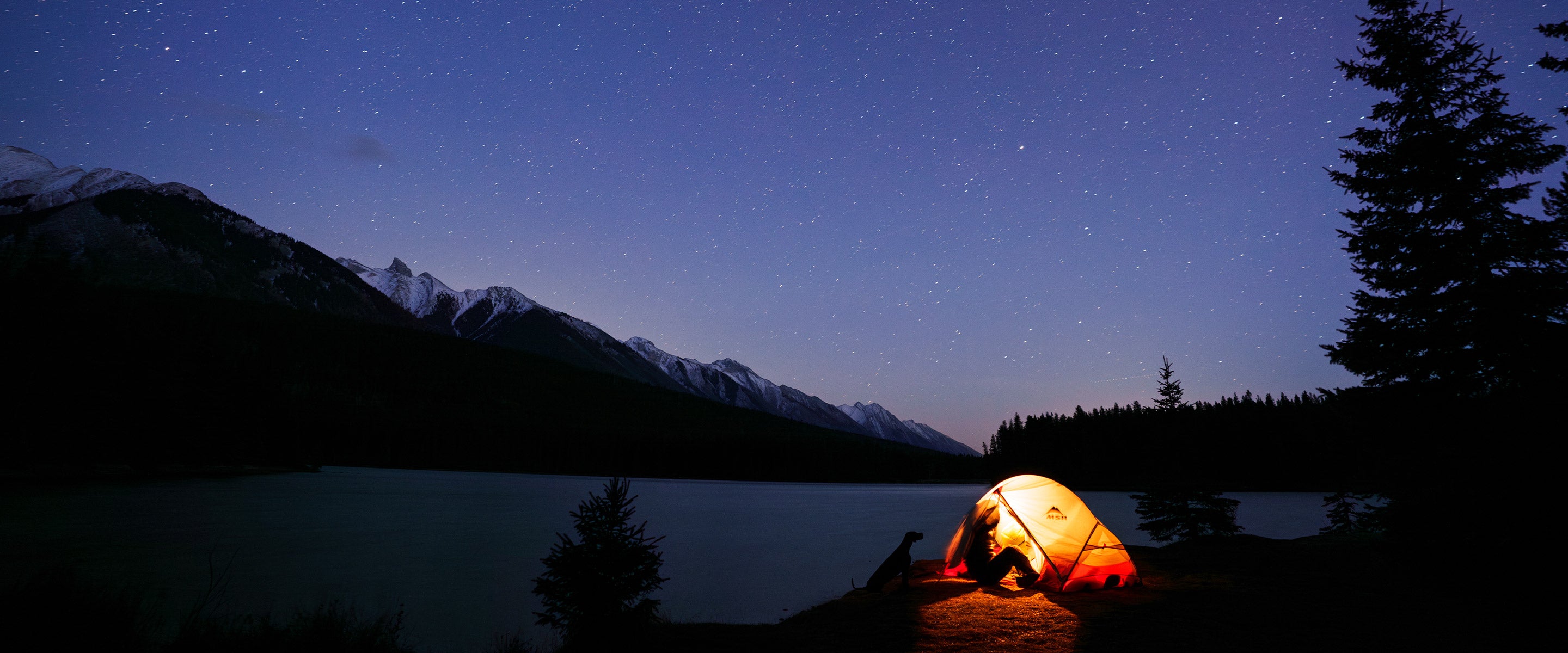 Woman in her tent at night in Banff with her dog for Säker photoshoot